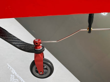 Close-up of black tail-wheel and visible suspension system on a gray background.