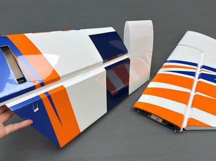 Colorful airplane tailplane with a hand holding it on a gray background