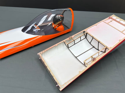 Two model airplane canopies on a gray surface
