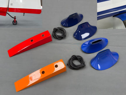 Colorful airplane parts including langing gear cuffs on a gray surface with a small airplane in the background.