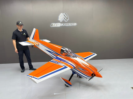 Person holding a remote control next to an orange and white model airplane in a showroom.