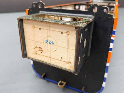 Wooden box with metal grid and number 224 on a gray surface