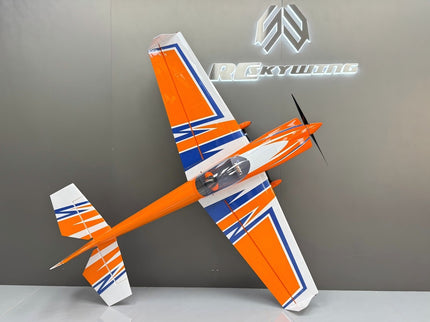 Orange and white model airplane on a gray surface with a brand logo in the background