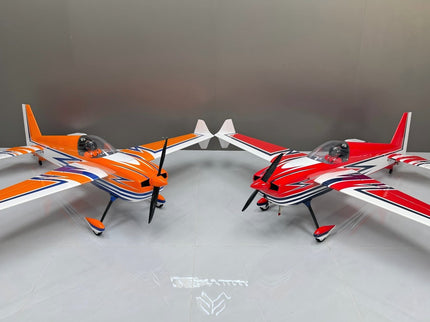 Two model airplanes, one orange and white, the other red and white, on a gray surface.