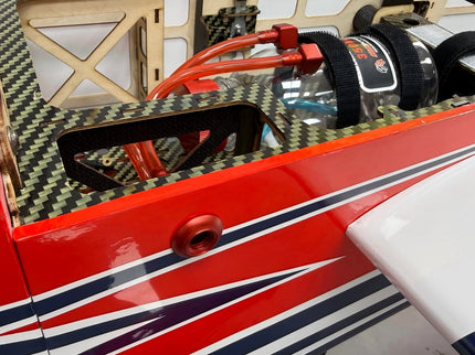 Close-up of a red and white model airplane with carbon fiber texture on the wing.