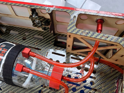 Close-up of a mechanical component with red and black wiring on a carbon fiber surface.