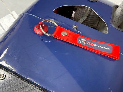 Red keychain with a logo attached to a blue surface