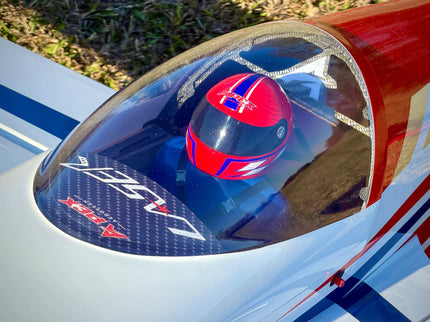 Close-up of a red, white, and blue canopy with a driver wearing a matching red, white, and blue helmet under a clear canopy.