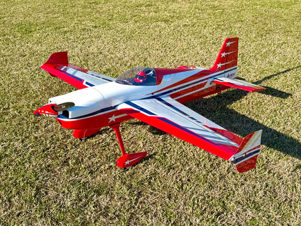 A red, white, and blue remote control airplane with star details, parked on a grassy lawn.