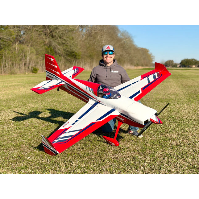 Person holding a red, white, and blue model airplane in an open field.