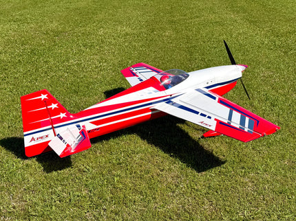 A red, white, and blue Apex model airplane resting on a green grass lawn.