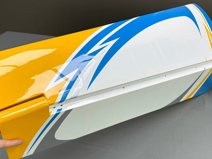 Colorful model airplane wing with a hand holding it against a dark background