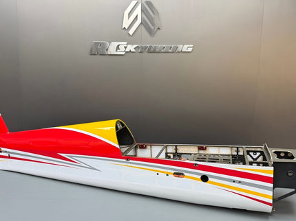 Model airplane with red, yellow, and white design on a gray surface with a brand logo in the background.