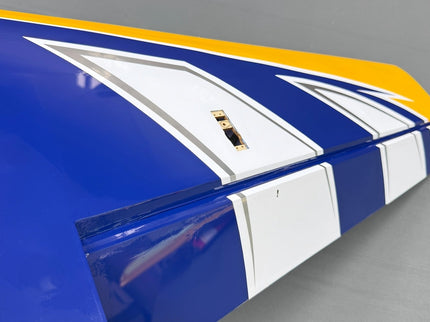 Close-up of a blue and white airplane wing with yellow accents on a gray background