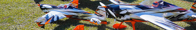 Apex Model airplanes on display at an outdoor event with tents and people in the background.