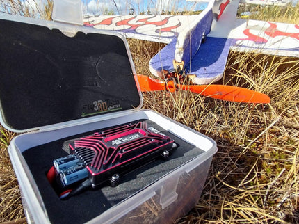 Open case with electronic device in a field with model airplane in background