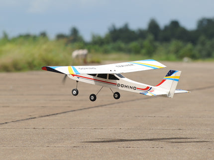 Phoenix Model Domino 62” Trainer Model airplane on a runway with trees in the background