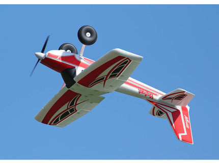 Red and white model airplane flying against a clear blue sky