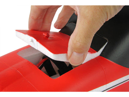 Person using a red and white tool on a black surface