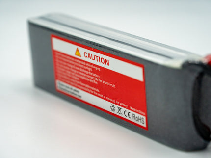 Battery with a red caution label on a light gray background