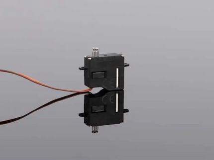 Black mechanical component with wires on a reflective gray surface