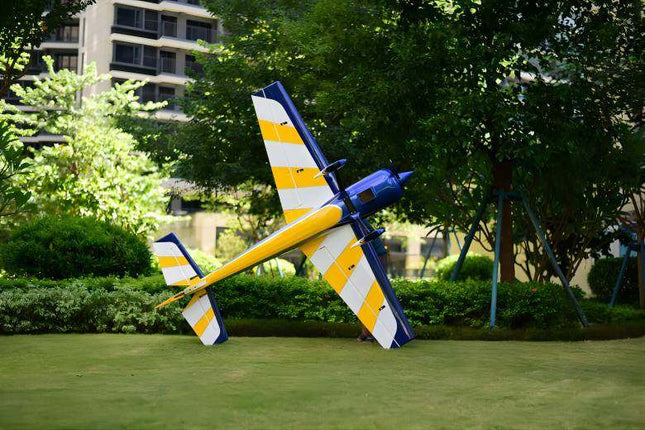 Colorful airplane model on grass with trees and buildings in the background