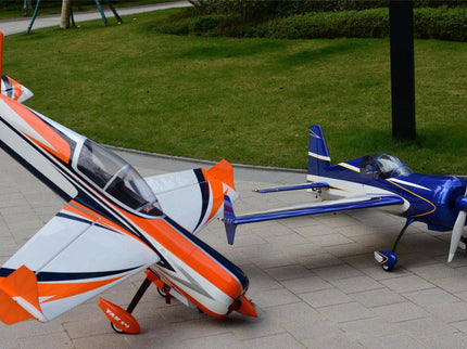 Two model airplanes on a paved surface with grass in the background