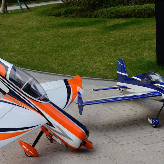 Two model airplanes on a paved surface with grass in the background