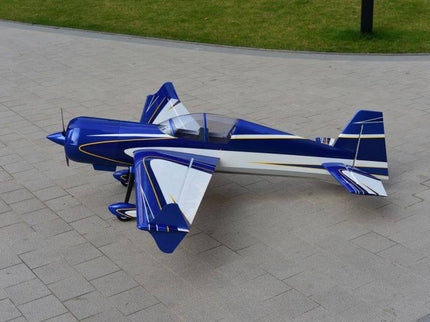 Blue and white model airplane on a paved surface with grass in the background