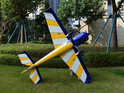Model airplane on grass with trees and buildings in the background