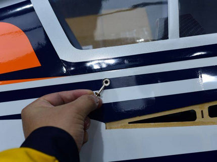 Hand holding a magnetic mounting pin for canopy with orange and blue design