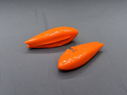 Two orange wheel pants on a gray surface