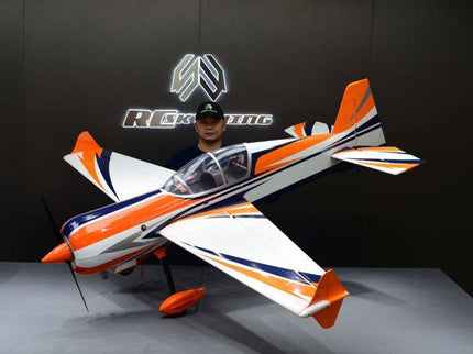 Orange and white model airplane on a gray surface with a dark background featuring a logo.