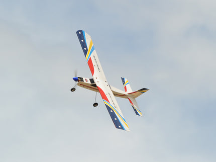Phoenix Model Domino 62” Trainer model airplane flying against a clear blue sky