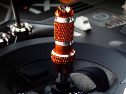 Close-up of a car gear shift knob with an orange and silver design on a vehicle interior.