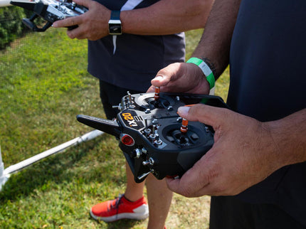 Person holding a drone controller with grass in the background