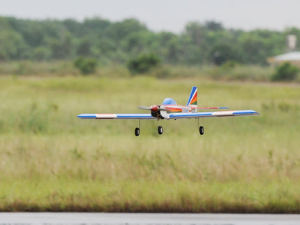 Phoenix Model PH006-SCANNER 57" Model airplane flying over a grassy field with trees in the background