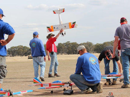 Group of people with Phoenix Model PH006-SCANNER 57" model airplanes on a dirt field