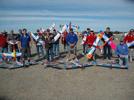 Group of people with Phoenix Model PH006-SCANNER 57" model airplanes on a sandy ground