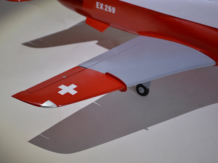 Close-up of a red and white airplane wing with a cross symbol on a light background