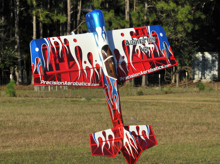 Red, white, and blue model airplane with 'Precision Aerobatics' branding on a grassy field.