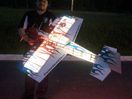 Person holding a large model airplane outdoors at night