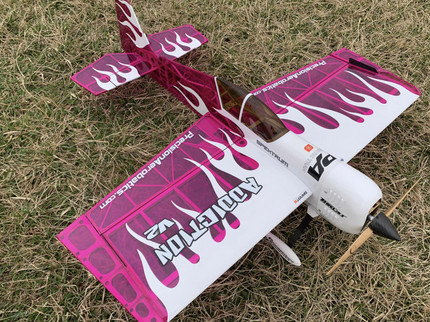 Pink and white model airplane on grass