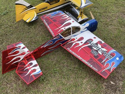 Two model airplanes on grass with one displaying branding.