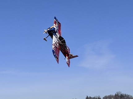 Colorful airplane performing a maneuver against a clear blue sky