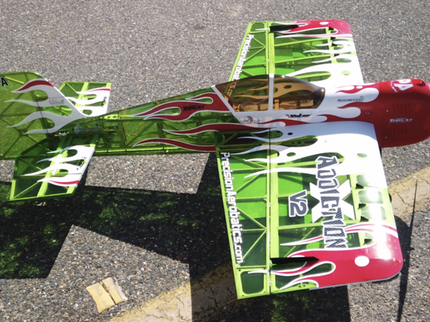 Model airplane with green and red design on a paved surface