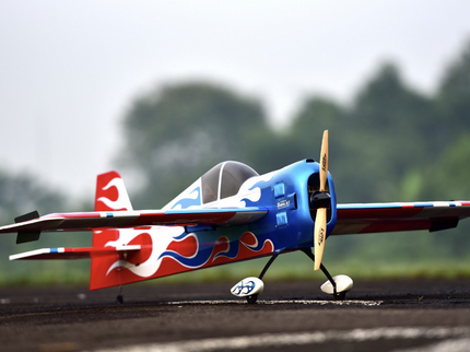 Model airplane on a runway with trees in the background