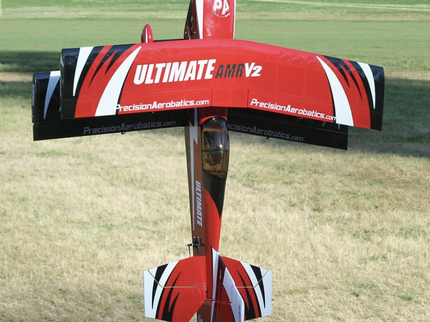 Red and black model airplane with 'Ultimate AMV2' branding on a grassy field.