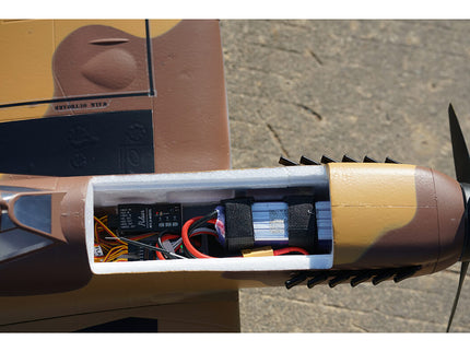 Close-up of a model airplane with visible wiring and components on a textured surface.
