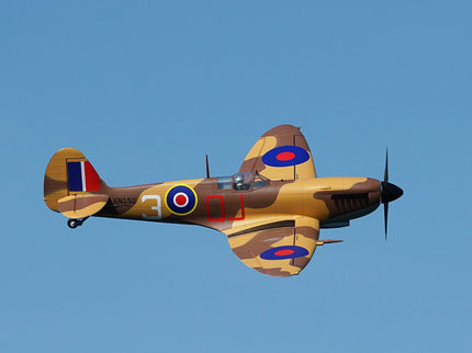 Camouflaged airplane with British roundel insignia flying against a clear blue sky